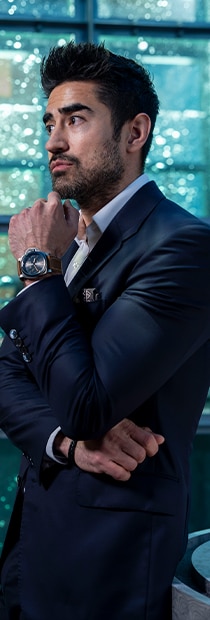Jeremy Jauncey in a dark suit with Panerai watch beside a glass wall