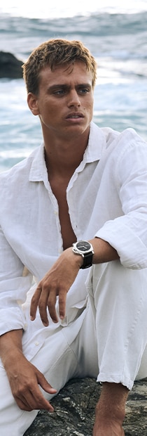 Kauli Vaast in a white shirt with Panerai watch seated outdoors